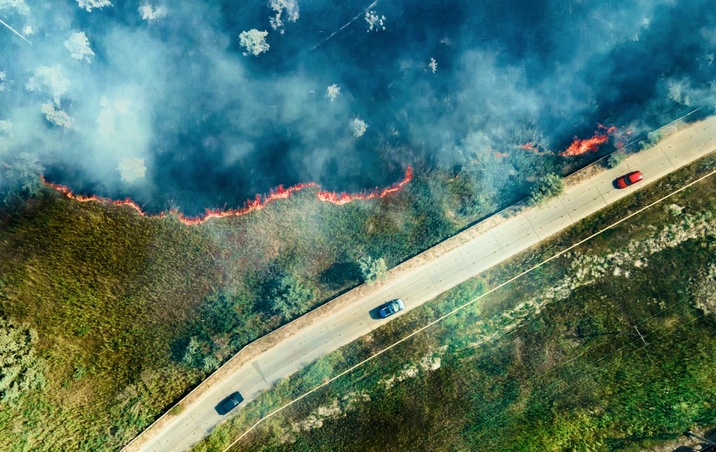 Satellite image of cars on a freeway with burning fire approaching