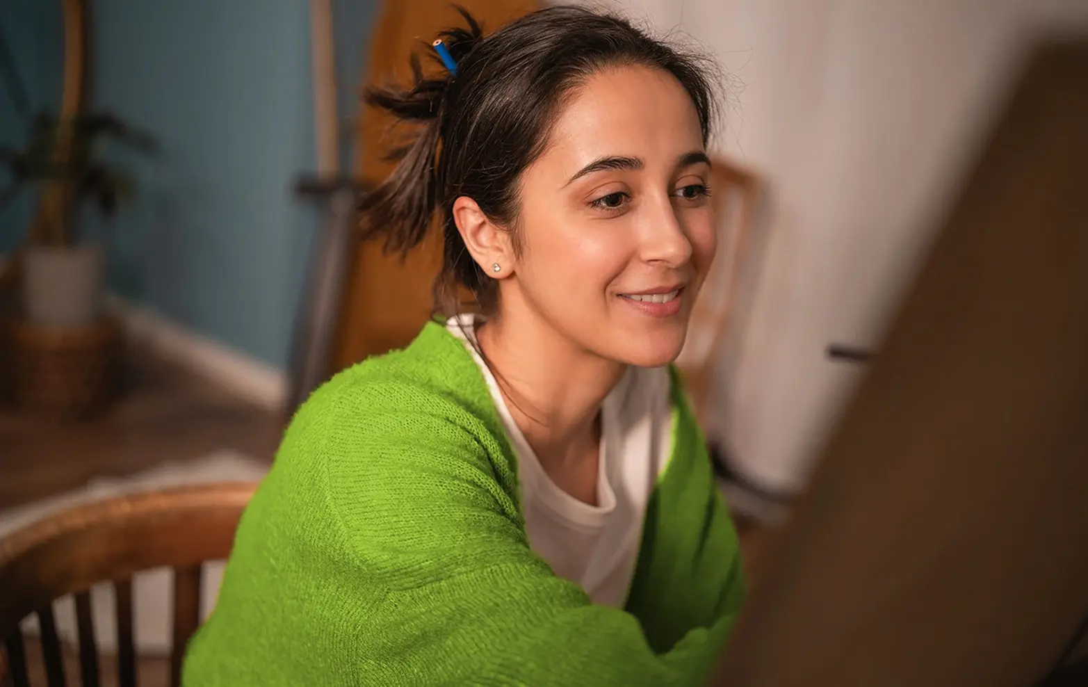 A creator at an easel looks toward an unseen monitor, using a digitally generated lighting setup from the 3D application as a reference for their physical painting.